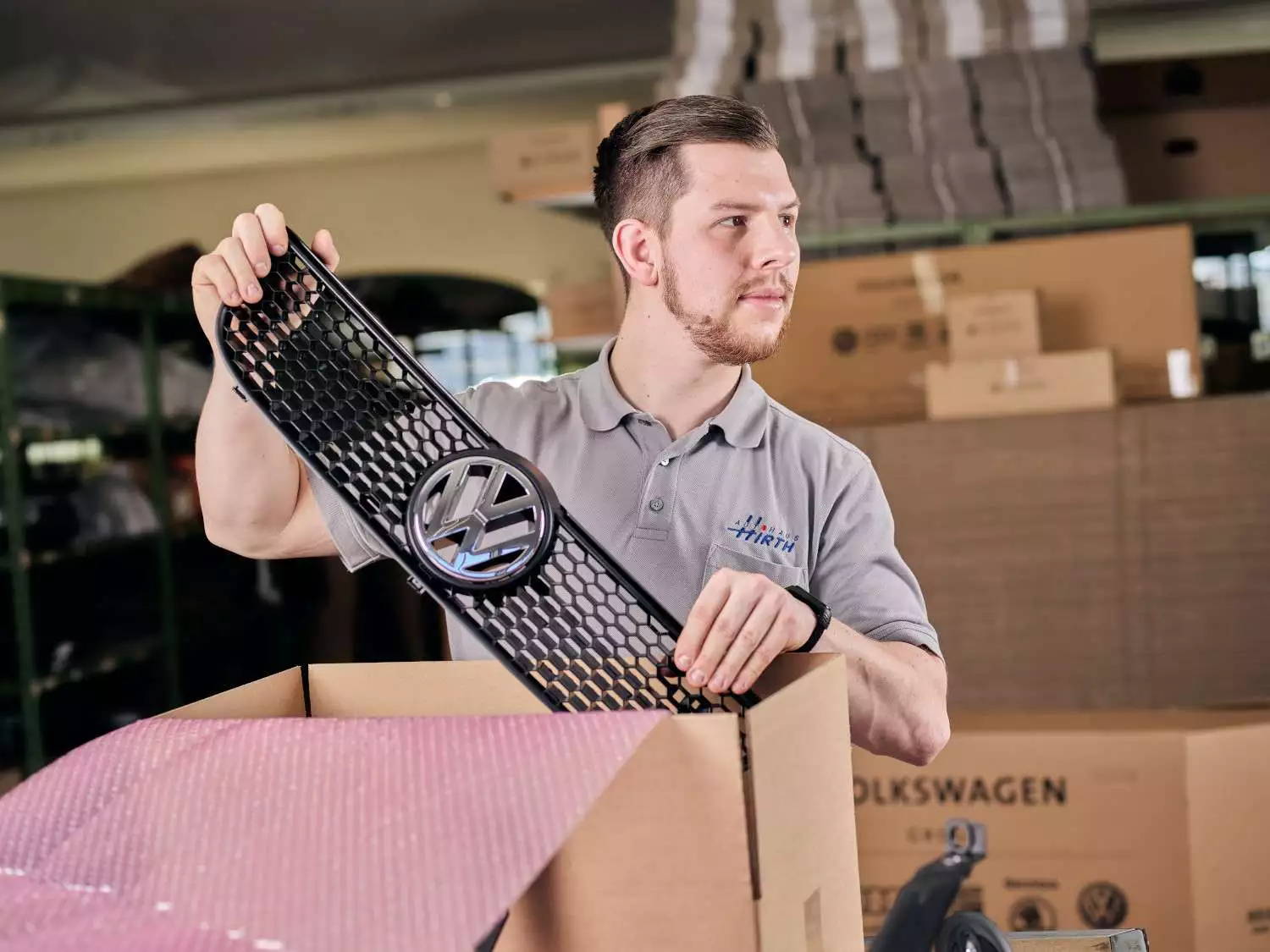 Ein Mitarbeiter entnimmt eine VW Frontgrill aus einem Paket